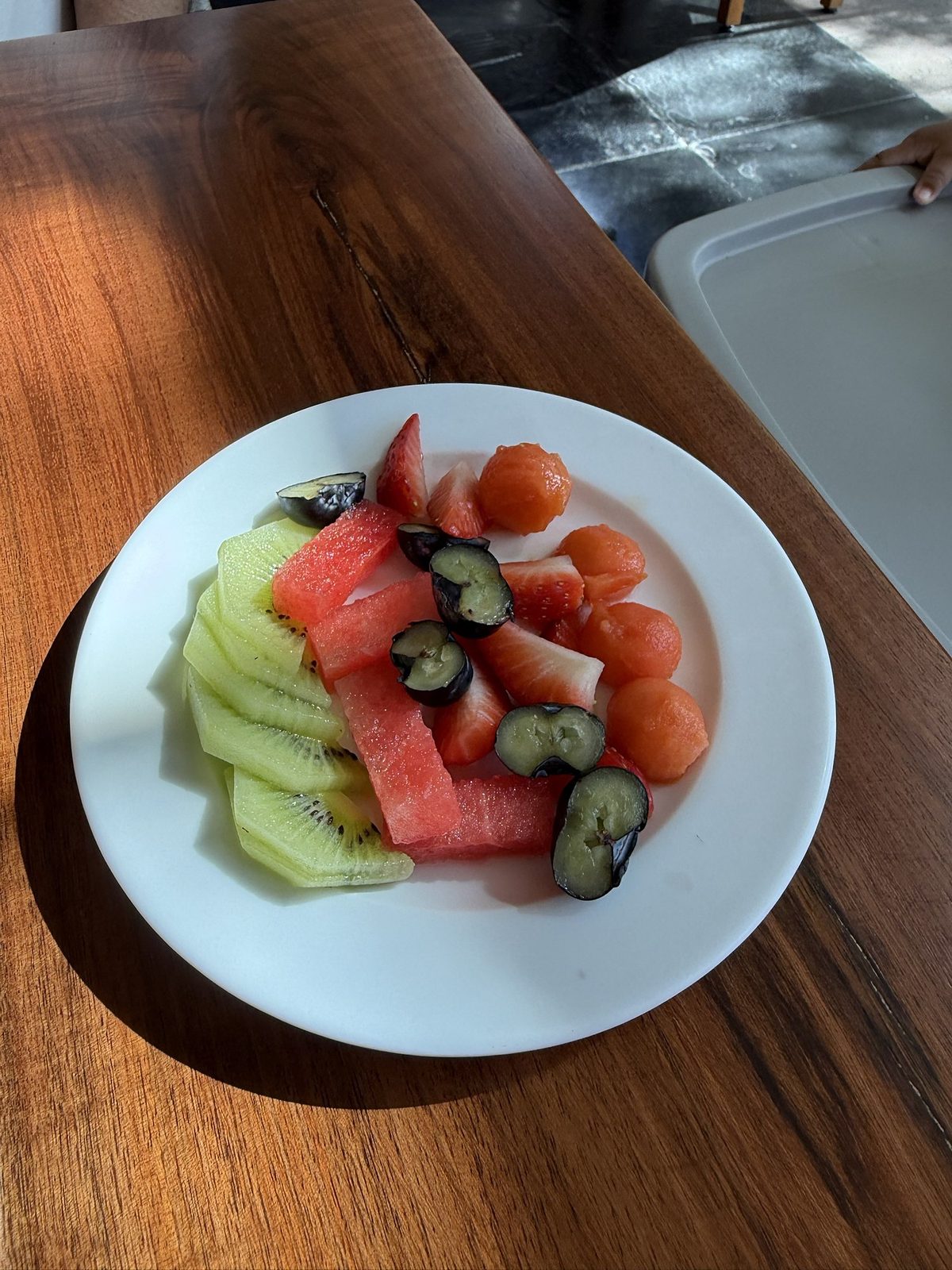 Plate of sliced kiwi, watermelon, strawberry, melon balls and grapes