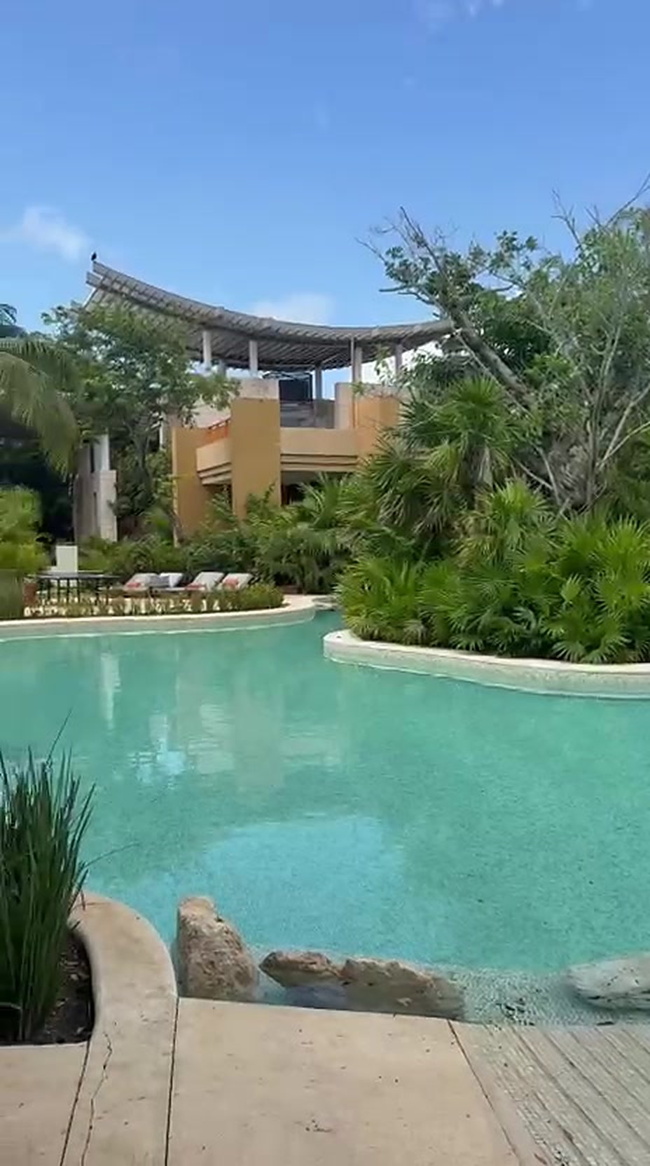 The quiet Reflections Pool at Banyan Tree Mayakoba, turquoise water edged with reeds and empty loungers under the resort's pagoda roofline