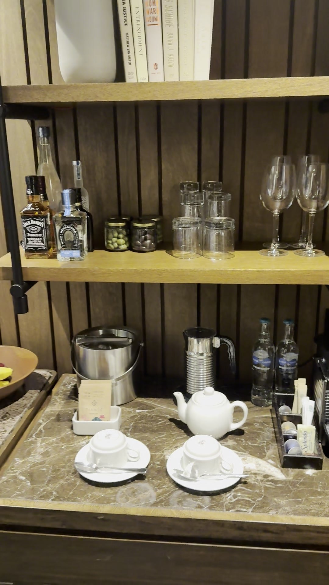 In-villa bar shelf with glassware, snacks, ice bucket, kettle, teapot and cups on a marble counter