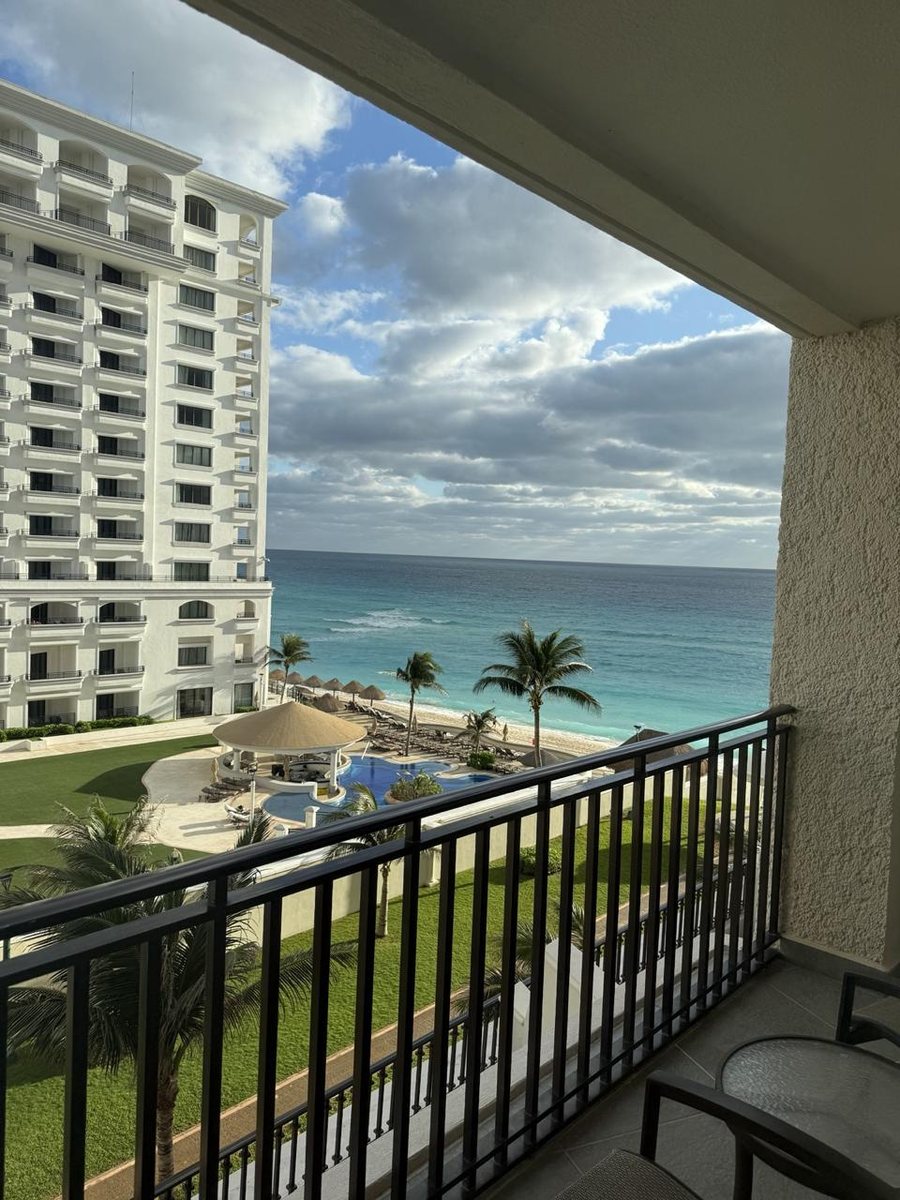 View from a Cancún Hotel Zone balcony showing the pool, beach, and the neighboring tower