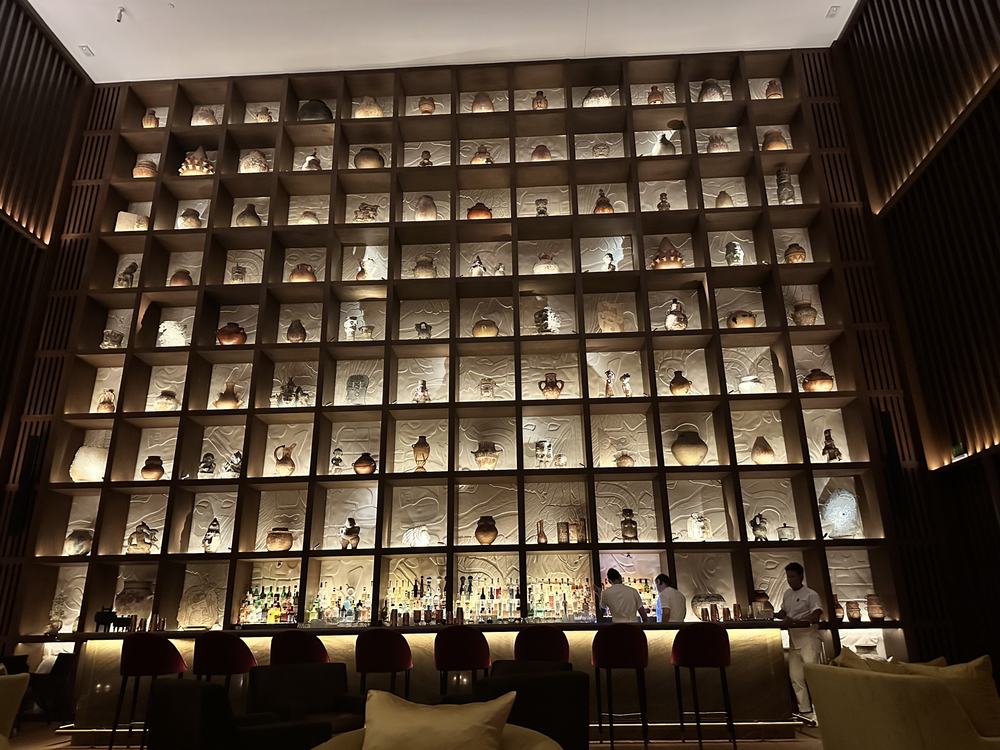 Floor-to-ceiling lit grid of Mexican pottery behind the bar at The Riviera Maya EDITION
