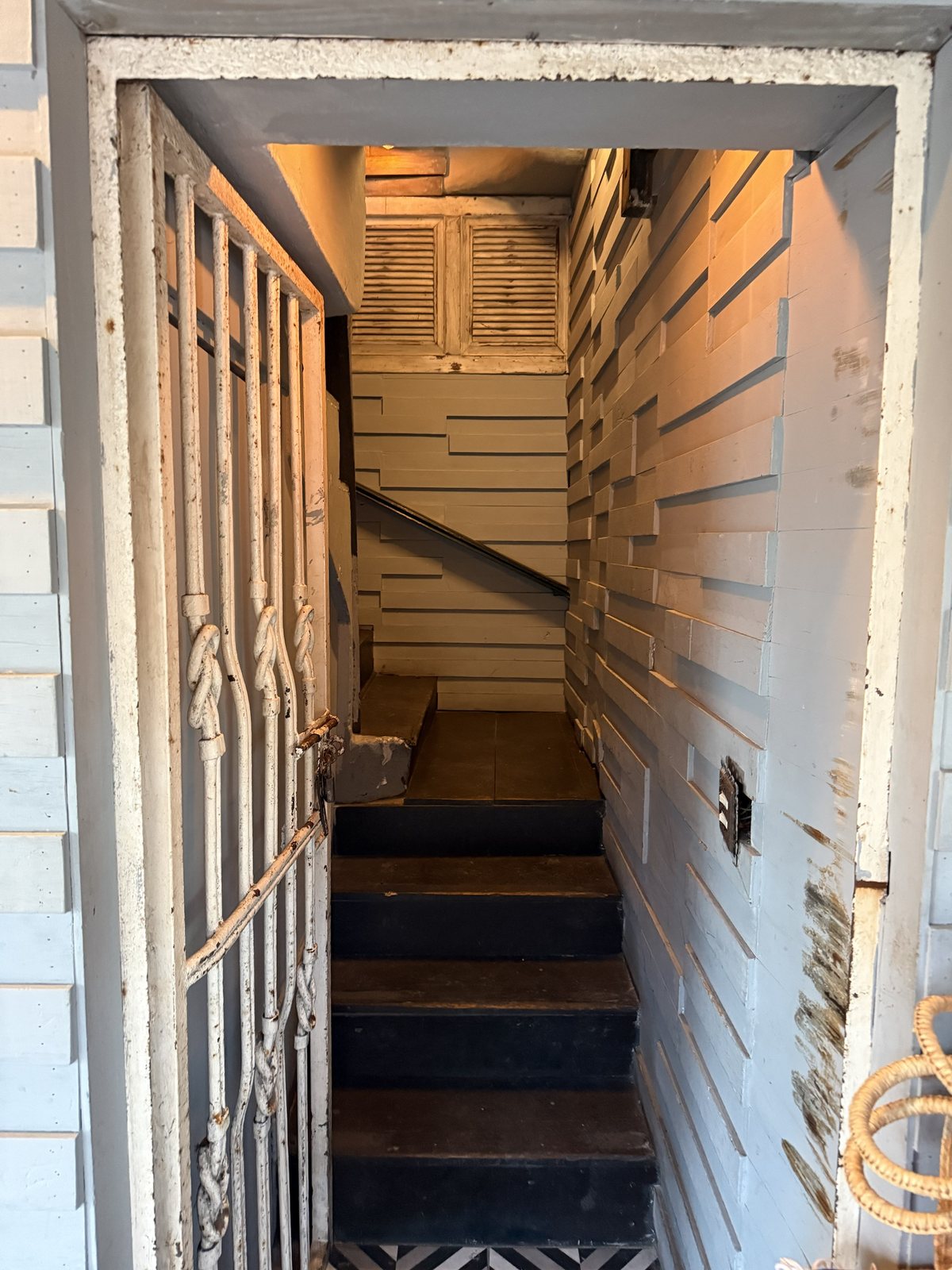 A narrow staircase with a metal handrail leading up from a souvenir shop to the restaurant on the second floor